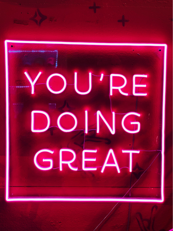 A pink neon sign that says you're doing great