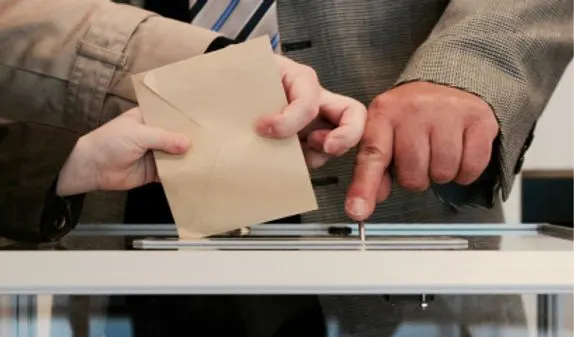 A poll worker guides a voter to cast their ballot